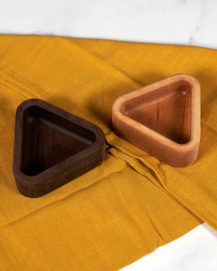 Triangular walnut and hard maple snack trays side by side on a gold linen runner.