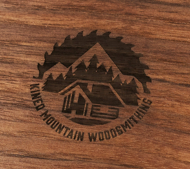 Custom laser engraving on wood by Kineo Mountain Woodsmithing, close-up of intricate engraved design on a wooden surface.