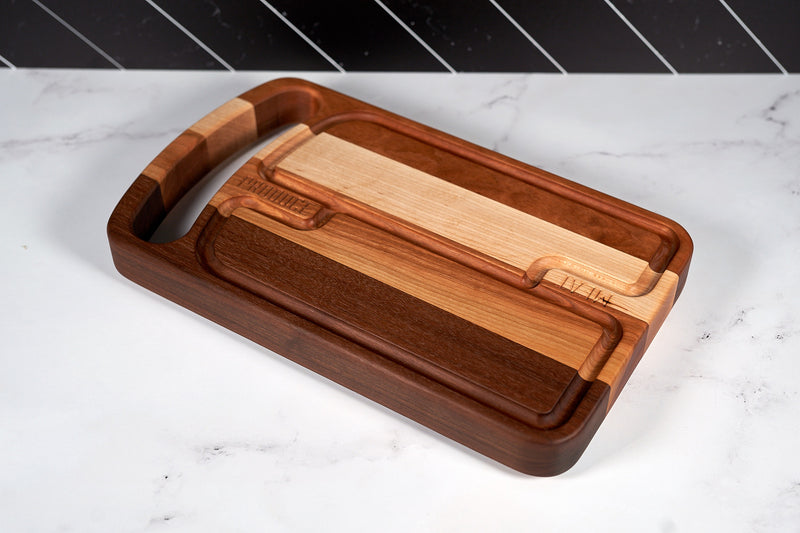 Black Walnut, Maple, and Cherry Duo-Zone Cutting Board by Kineo Mountain Woodsmithing, 16x9.5 inches, showing smooth wood surfaces and dual zones.