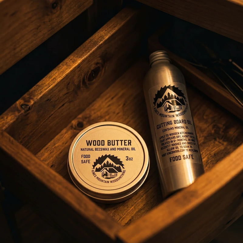 wood butter tin and cutting board oil bottle neatly arranged in a wooden drawer with warm lighting.