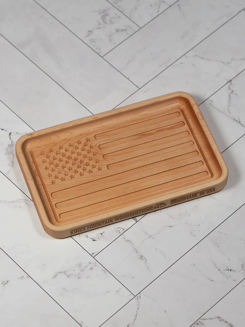 Hard maple American flag catchall tray with the flag carved into the floor, on white marble.