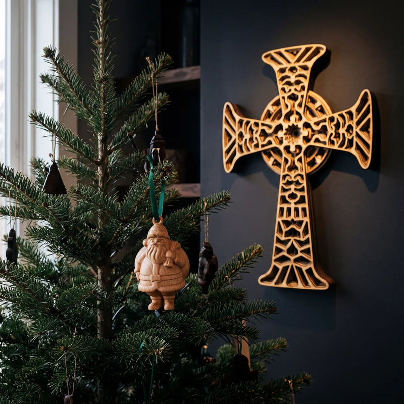Handcrafted maple carved Santa ornament displayed on Christmas tree in cozy holiday setting.