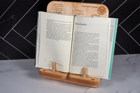 Premium maple cookbook holder with conversion chart propping open a cookbook on white marble kitchen countertop.