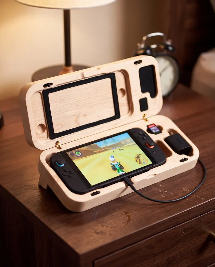 Hard maple travel case open on a nightstand with a Nintendo Switch 2 charging inside.