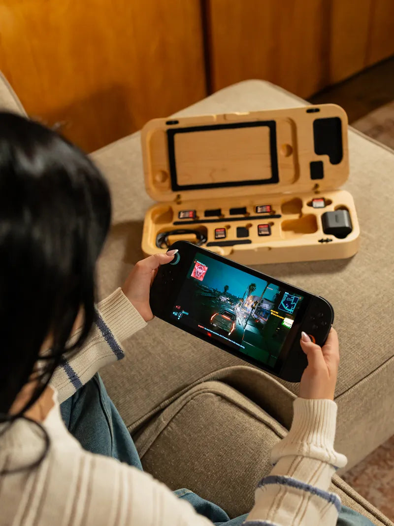 Hard maple travel case open on a couch showing the game card slots while someone plays.