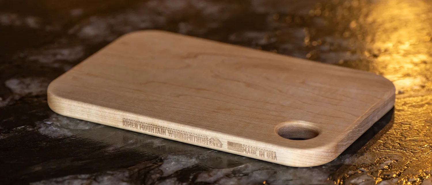 Small maple cutting board in warm evening light on a kitchen counter.
