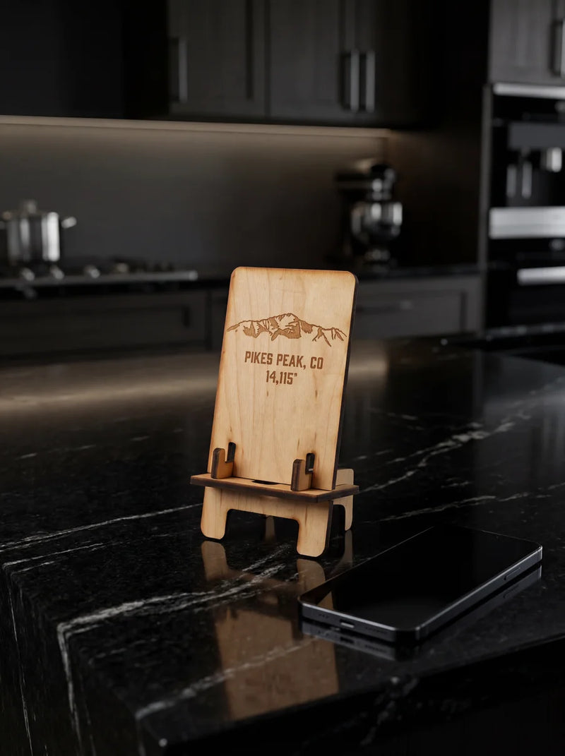 Maple phone stand displayed on black marble kitchen counter in modern luxury kitchen with smartphone.