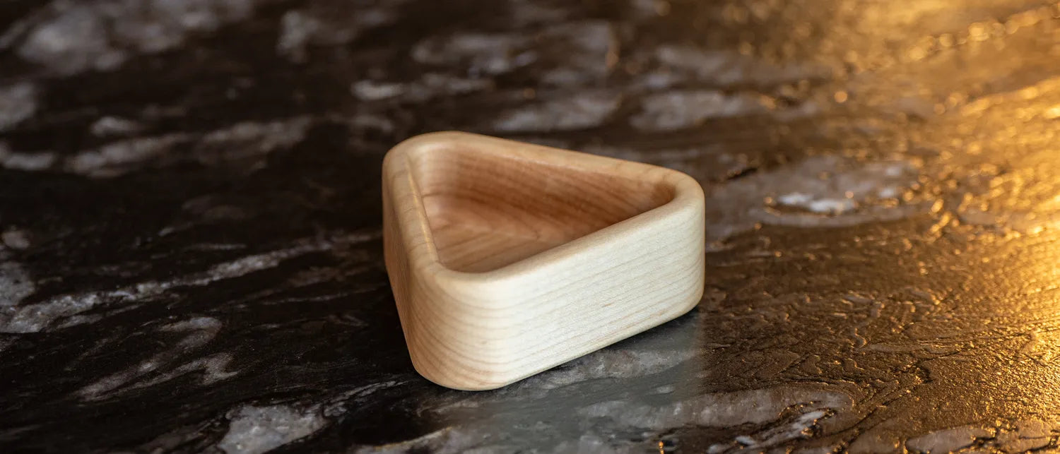 Triangular hard maple snack tray on a black stone kitchen counter.