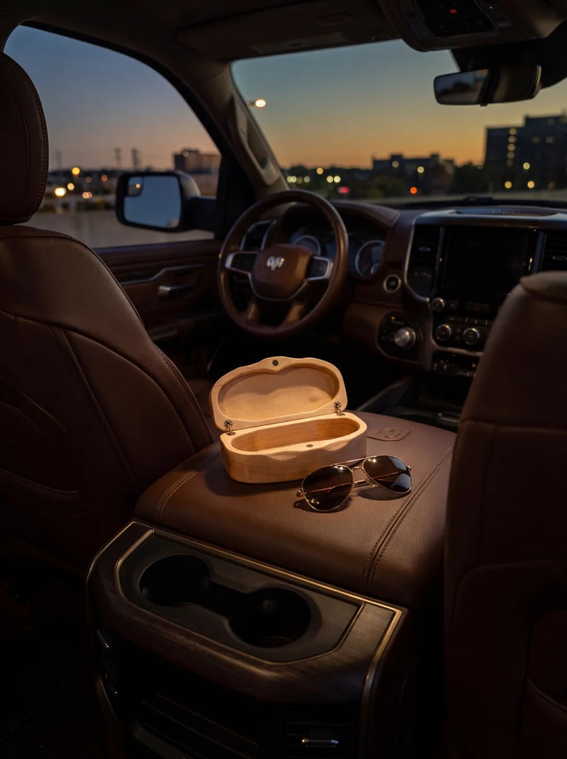 Elegant maple sunglasses case displayed open with sunglasses on console inside premium vehicle at twilight.