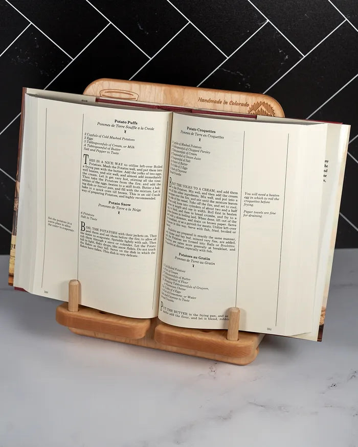Walnut cookbook stand with the dowel rods holding open the pages of a hardcover book.