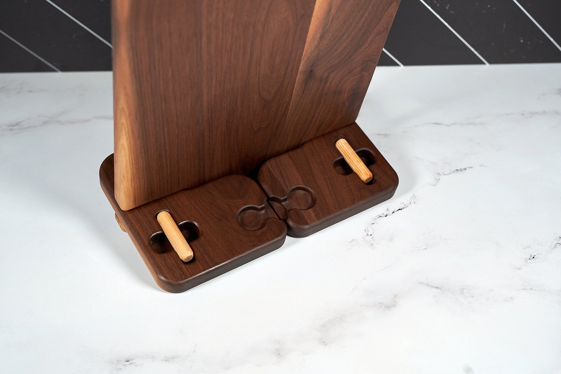 Walnut cookbook stand with conversion chart on white marble counter in modern kitchen with black tile backsplash.