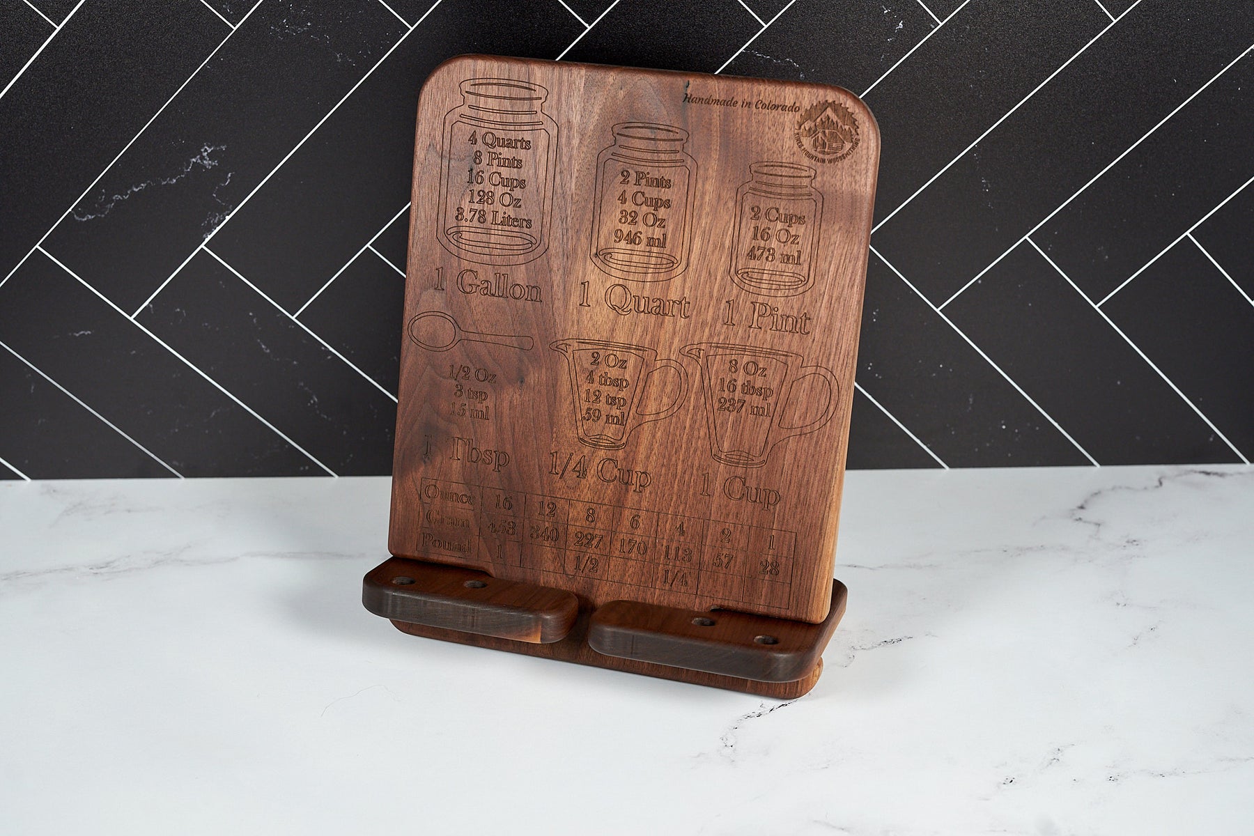 Elegant walnut conversion chart stand displayed on white marble countertop against black tile wall in kitchen.
