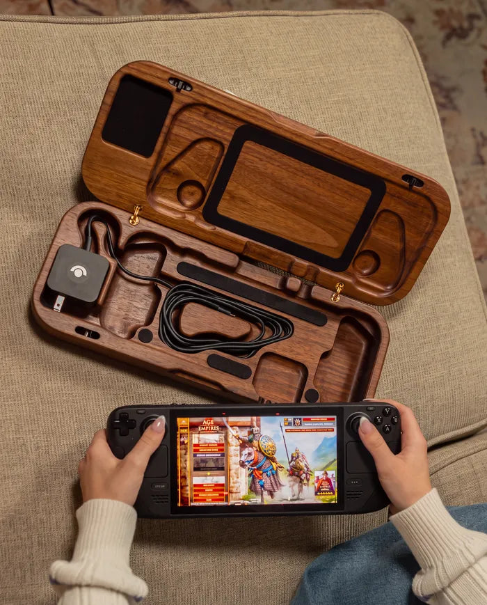 Walnut travel case open on a couch beside hands holding a Steam Deck.